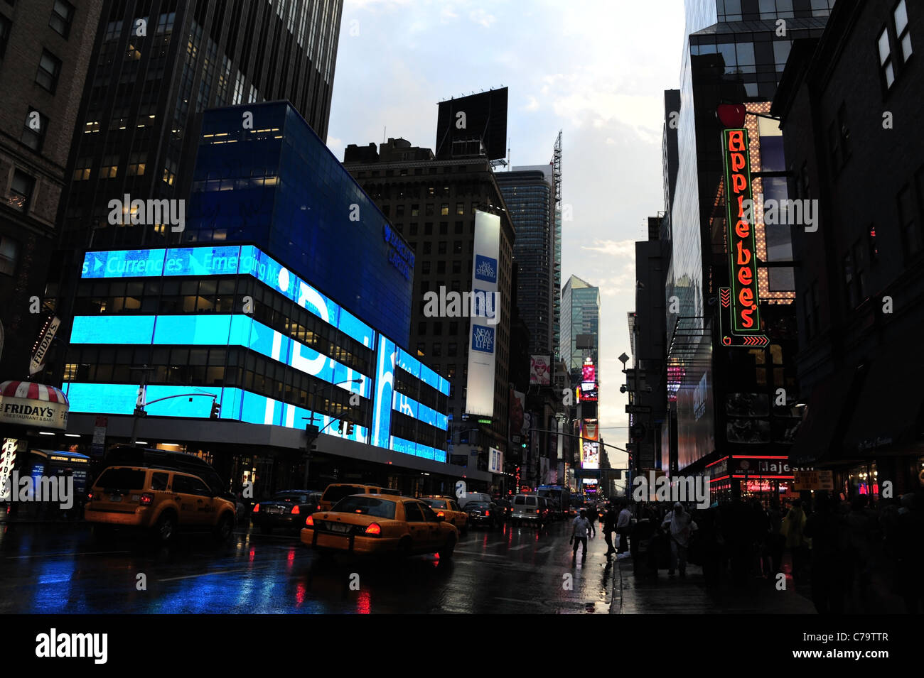 Crepuscolo vista pioggia, a sud verso Times Square, della Settima Avenue con i taxi gialli e blu neon, vicino Applebee's, New York City Foto Stock