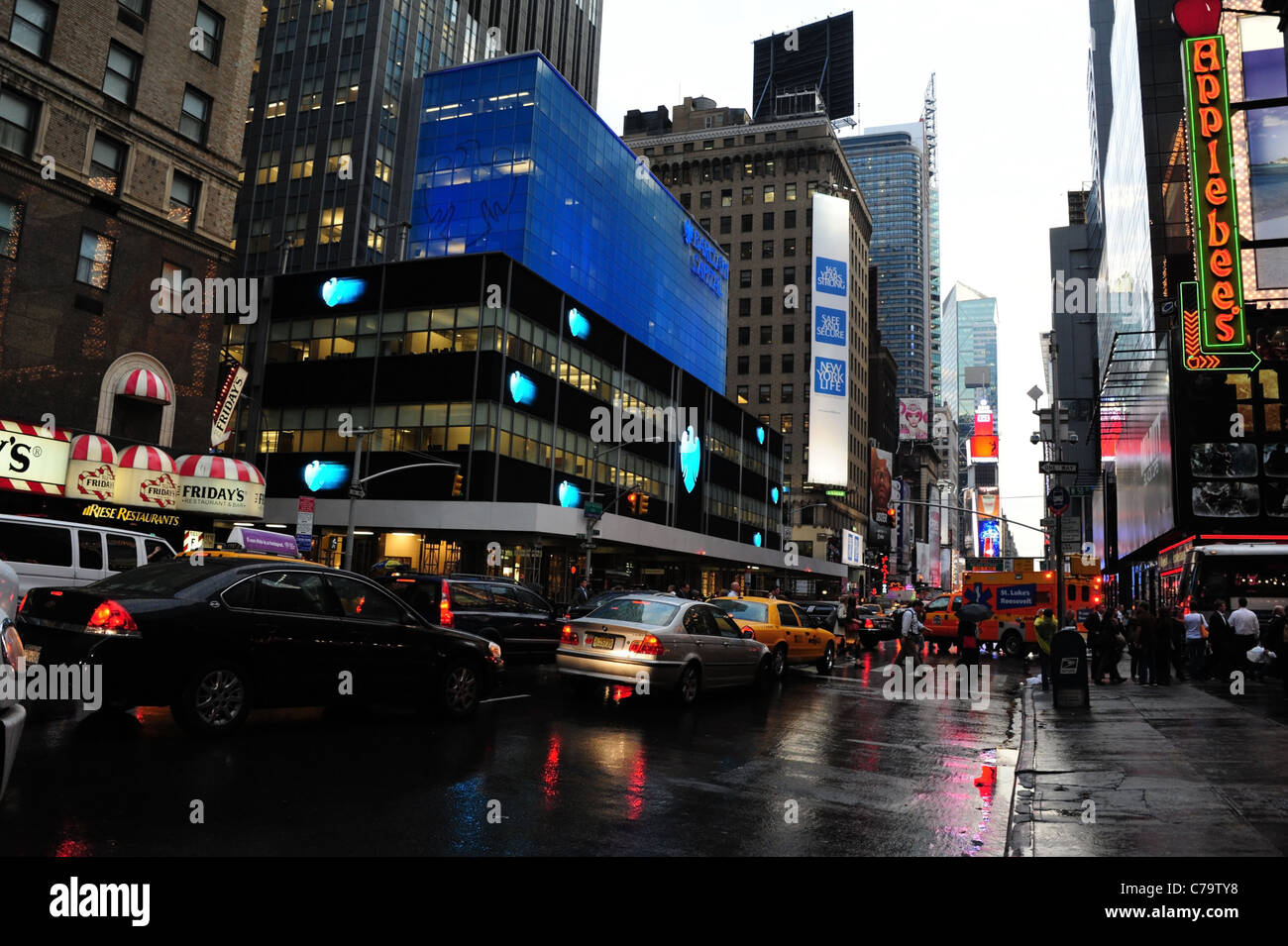 Piovosa asfalto bagnato visualizzare il traffico di persone in blu le insegne al neon Barclays Bank Applebee's, 7th Avenue, verso Times Square di New York City Foto Stock