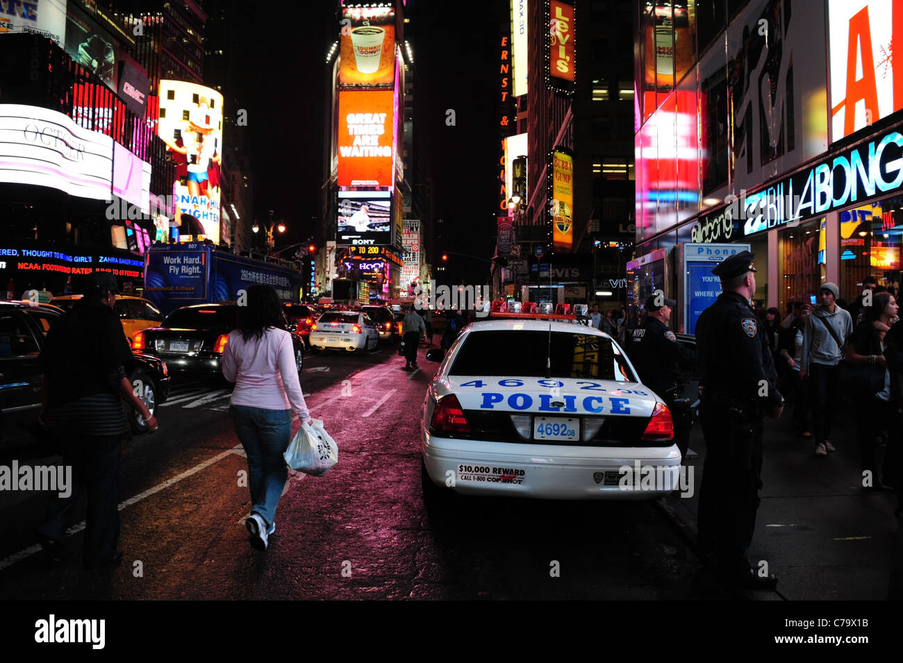 Vista notte marciapiede poliziotti, parcheggiato auto della polizia, gente che passeggia, traffico, neon, 7th Avenue, Times Square a New York City, Stati Uniti d'America Foto Stock