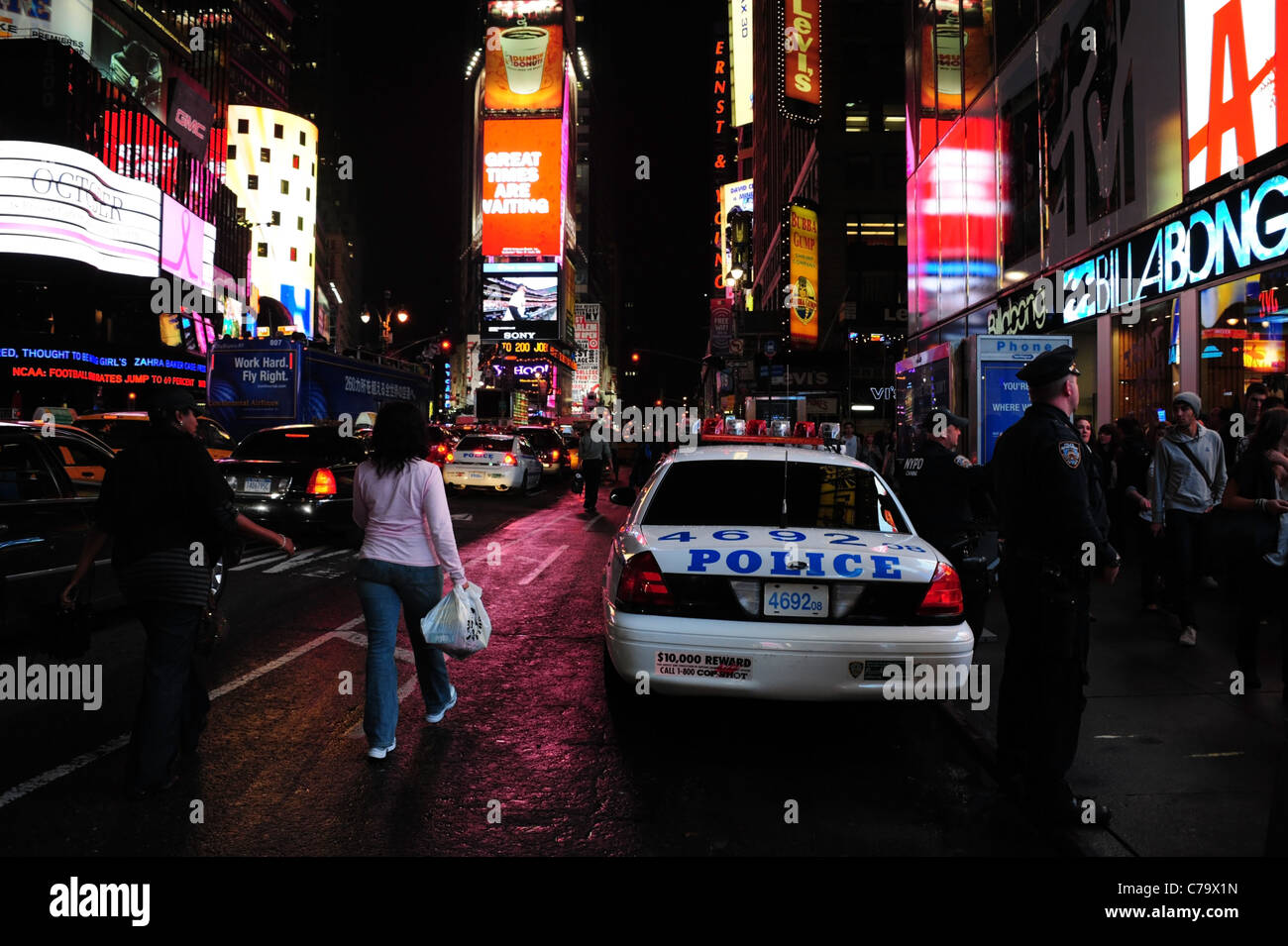 Vista notturna di insegne al neon, traffico di persone, parcheggiato auto della polizia e poliziotti sul marciapiede, 7th Avenue, Times Square a New York City Foto Stock