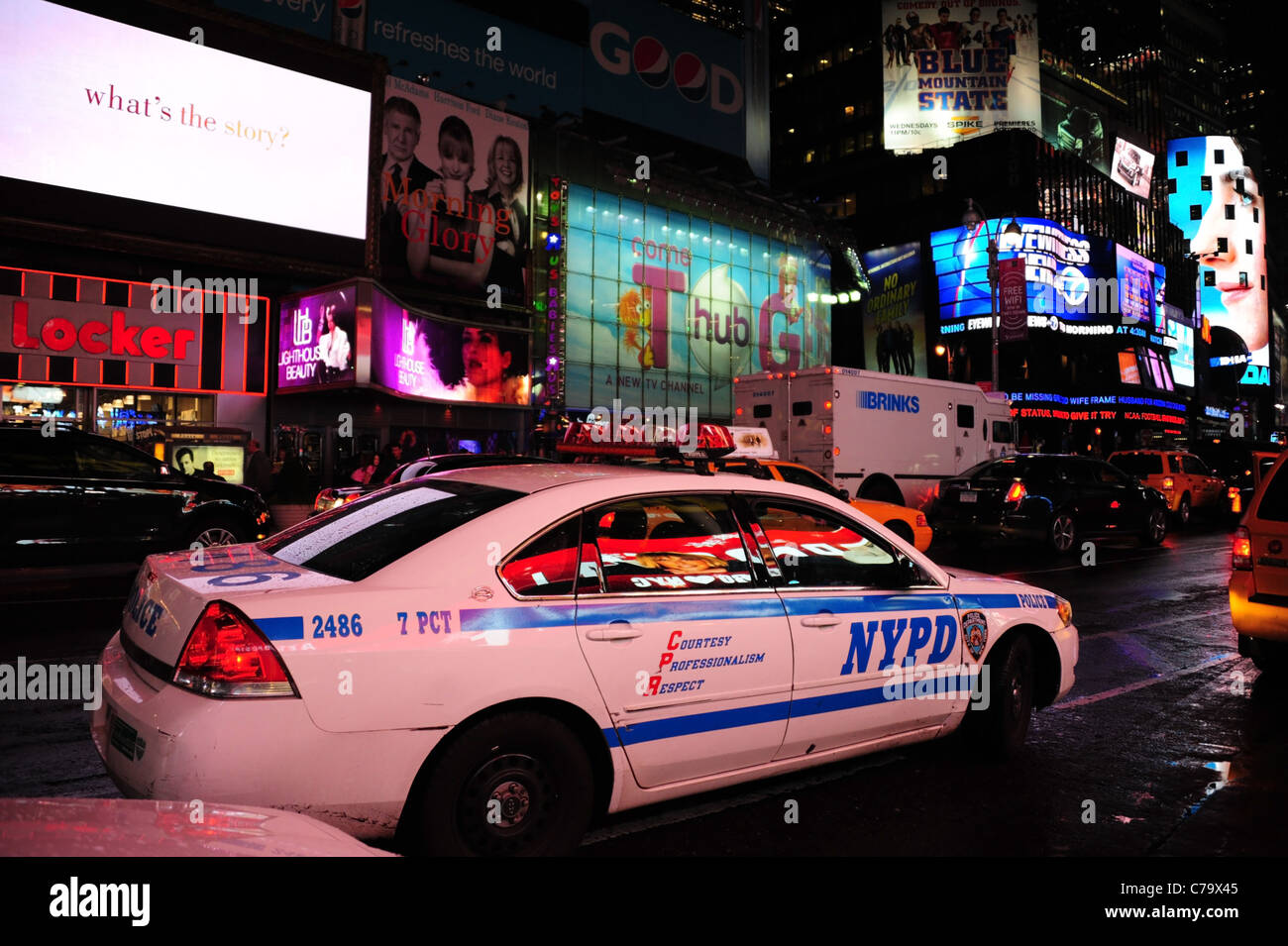 Vista notturna di NYPD bianco patrol auto parcheggiate a lato della Settima Avenue di fronte insegne al neon, Times Square a New York City Foto Stock