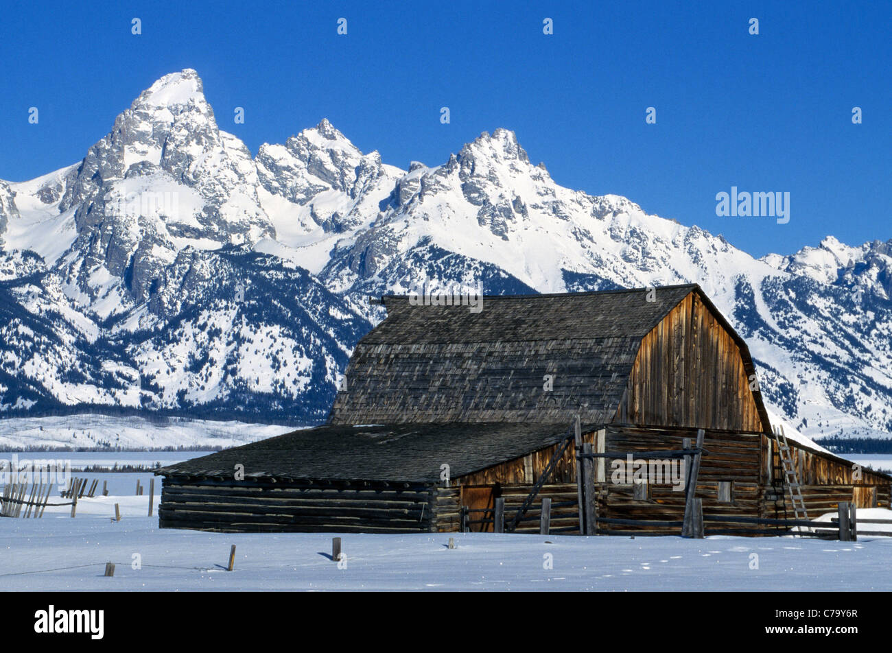 Un vecchio fienile spiovente è sopraffatte da neve-coperta Grand Teton Mountains nella stagione invernale in Jackson Hole, Wyoming negli Stati Uniti. Foto Stock