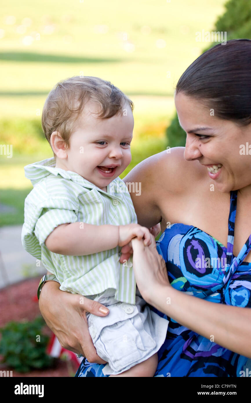 Una giovane madre solletica il suo bambino felicemente. Foto Stock