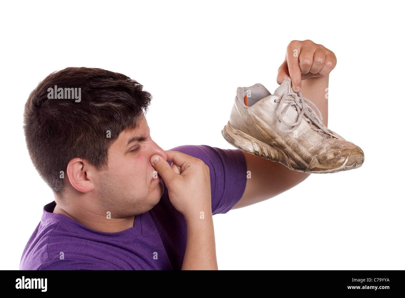 Un adolescente pizzichi le sue narici chiuso sopra l'odore dato fuori dalla scarpa da ginnastica egli è in possesso. Foto Stock