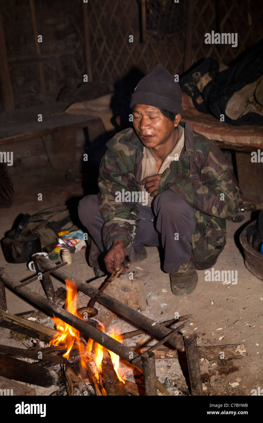 India, Nagaland, Longwa, Konyak Naga uomo seduto round fire fusione di oppio sul cucchiaio Foto Stock