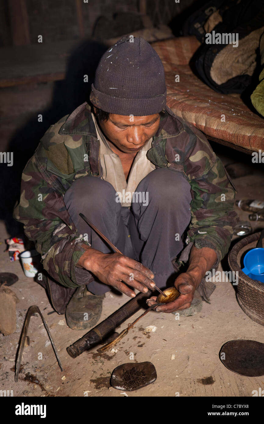 India, Nagaland, Longwa, Konyak Naga uomo agitazione oppio sul cucchiaio Foto Stock