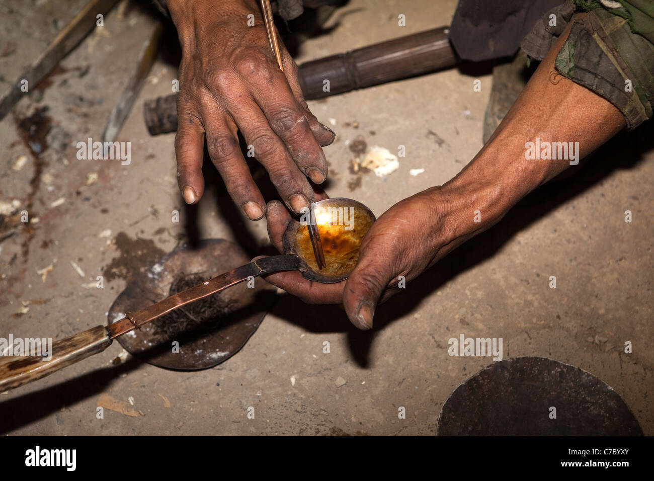 India, Nagaland, Longwa, mani di Konyak Naga uomo agitazione oppio sul cucchiaio Foto Stock