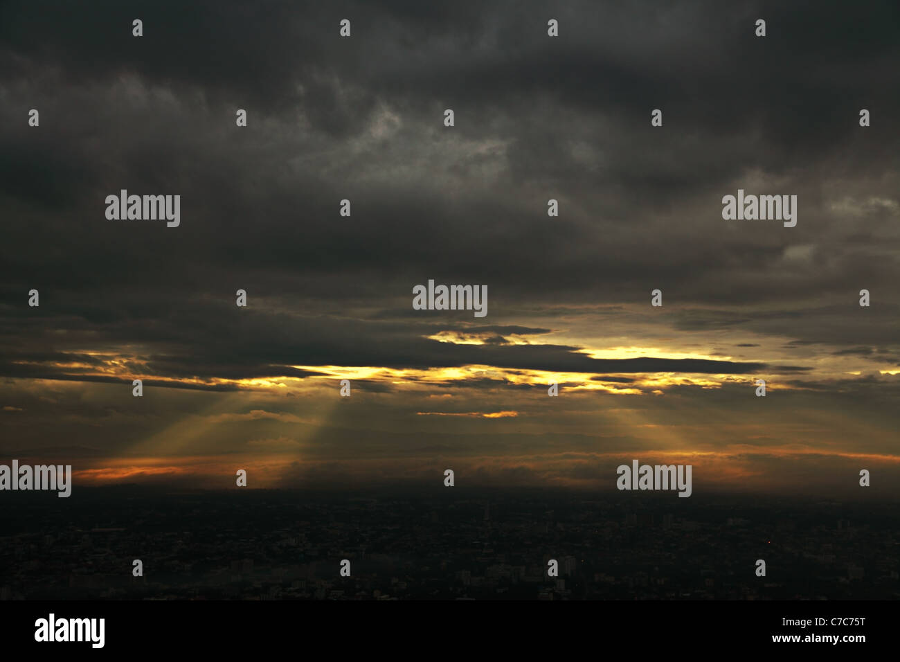 Raggi di sole lo scoppio attraverso un cielo nuvoloso scuro Foto Stock