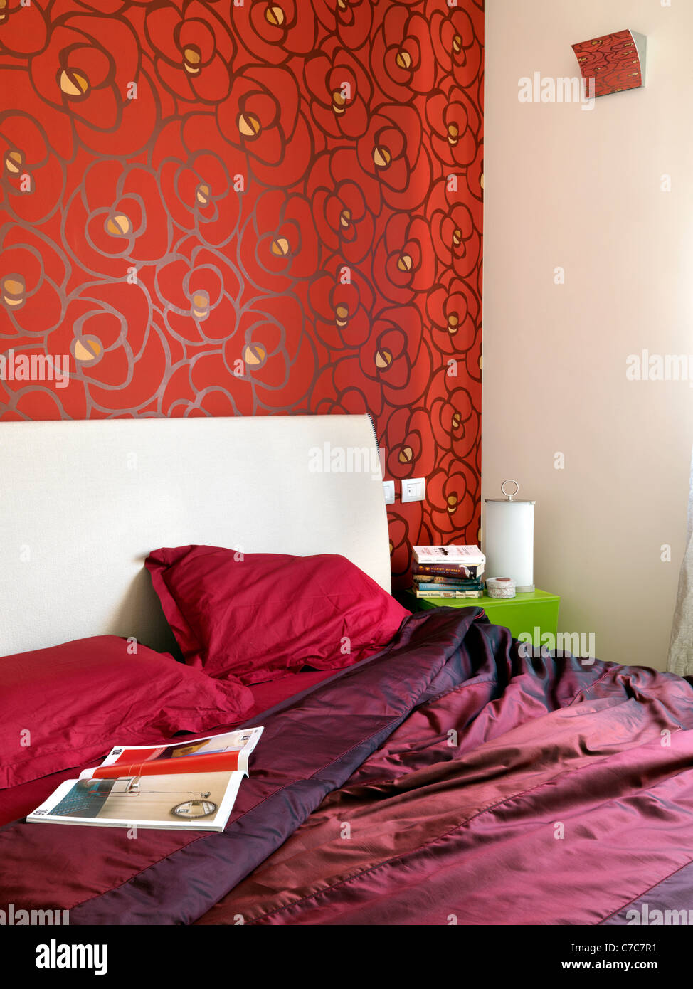 Dettaglio di una camera da letto con lenzuola rosse e tappezzeria di colore rosso su pareti Foto Stock