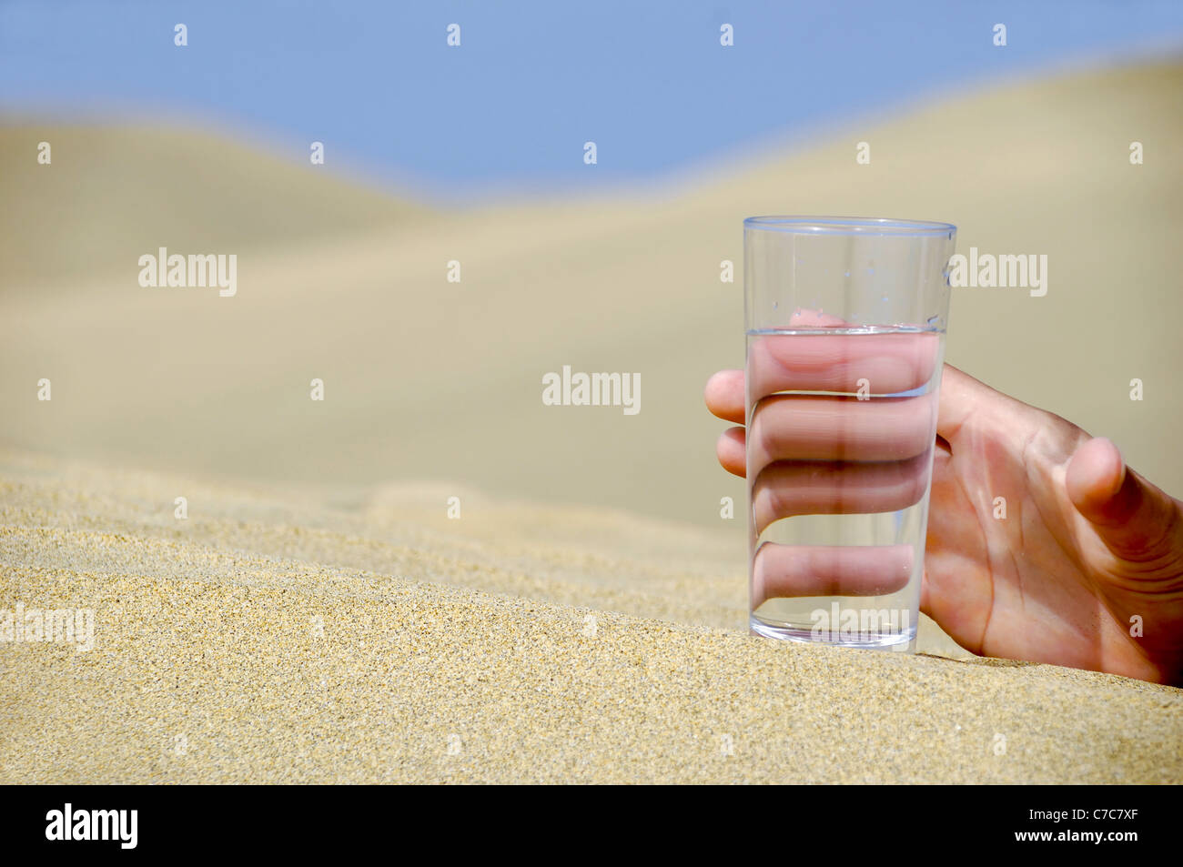 Mano è il raggiungimento di un fresco bicchiere di acqua fredda nel deserto. Foto Stock