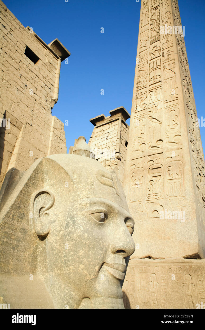 Testa dal seduto colossale statua di Ramses II e l'obelisco al primo pilone del Tempio di Luxor Luxor Egitto Foto Stock