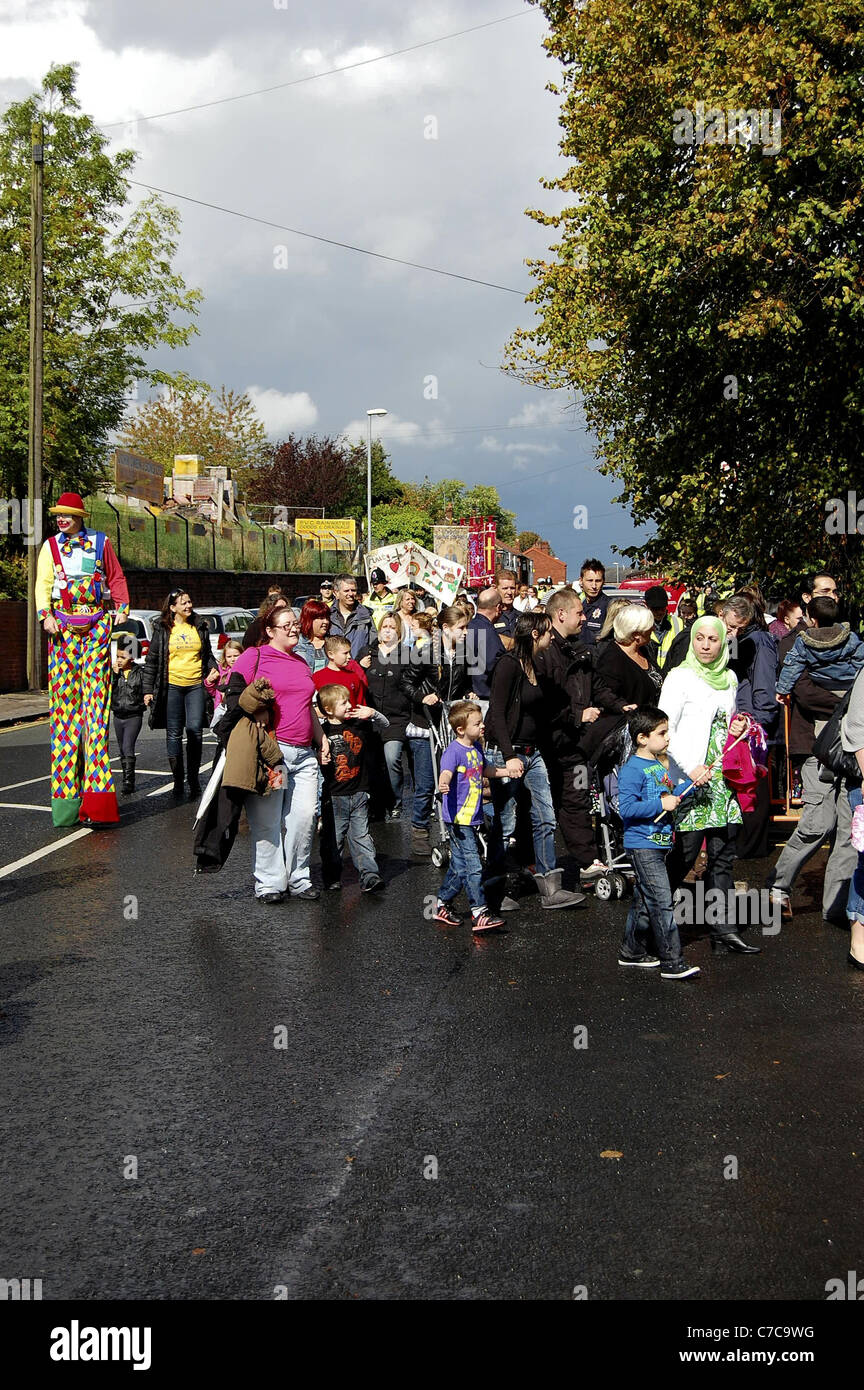 Costume clown su palafitte in Gorton parade Foto Stock