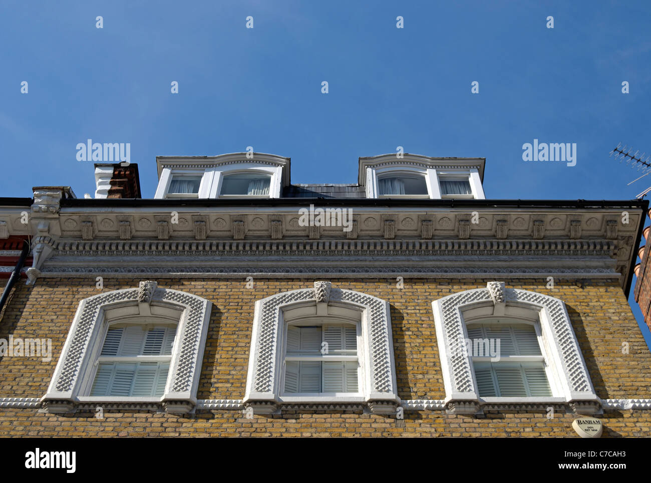 Dettaglio di 1870s house a South Kensington, Londra, Inghilterra, con tre finestre a ghigliottina al di sotto di una cornice modanata Foto Stock