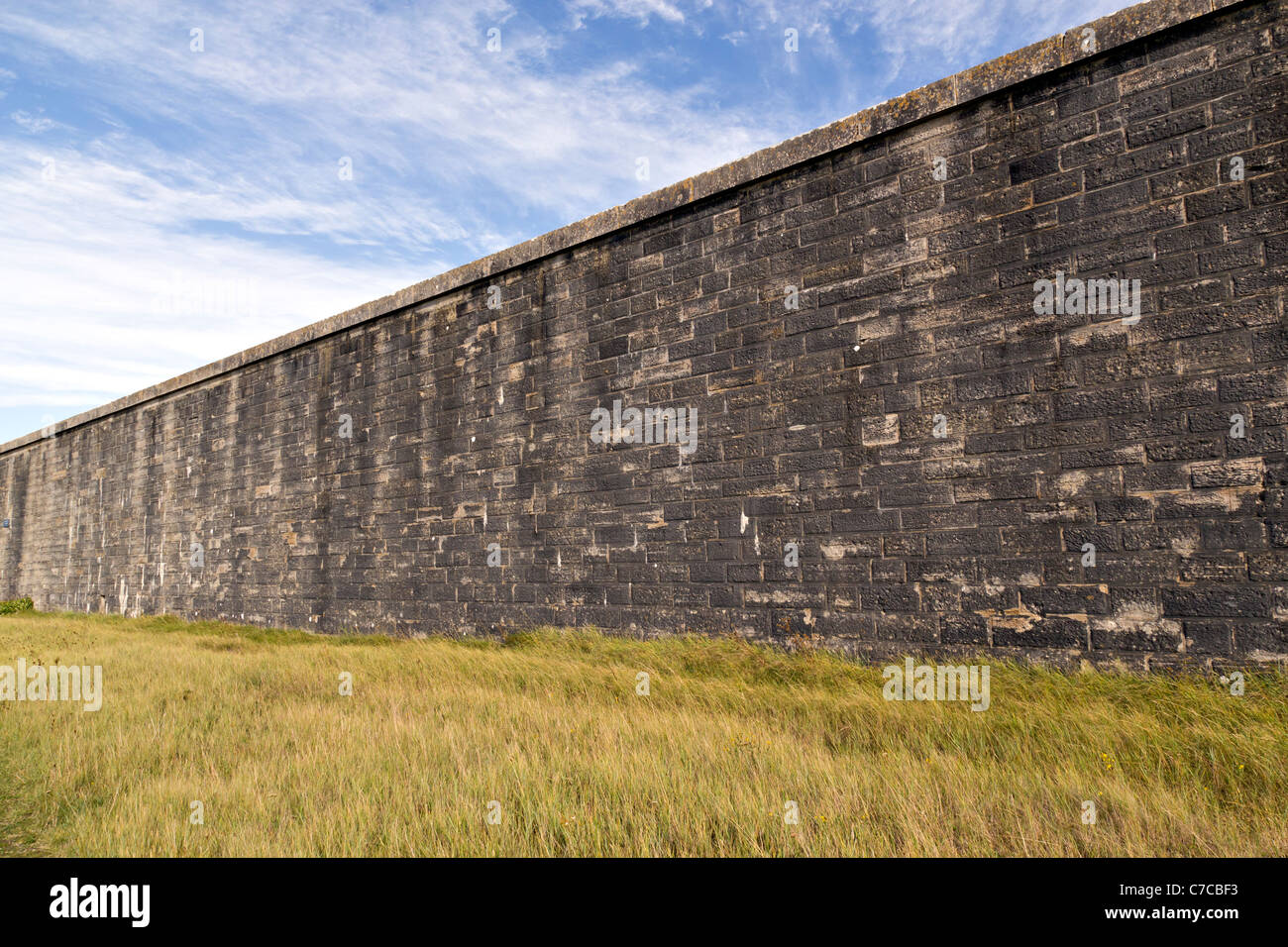 Pietra massiccio muro di castello con il blu del cielo e il verde erba Foto Stock