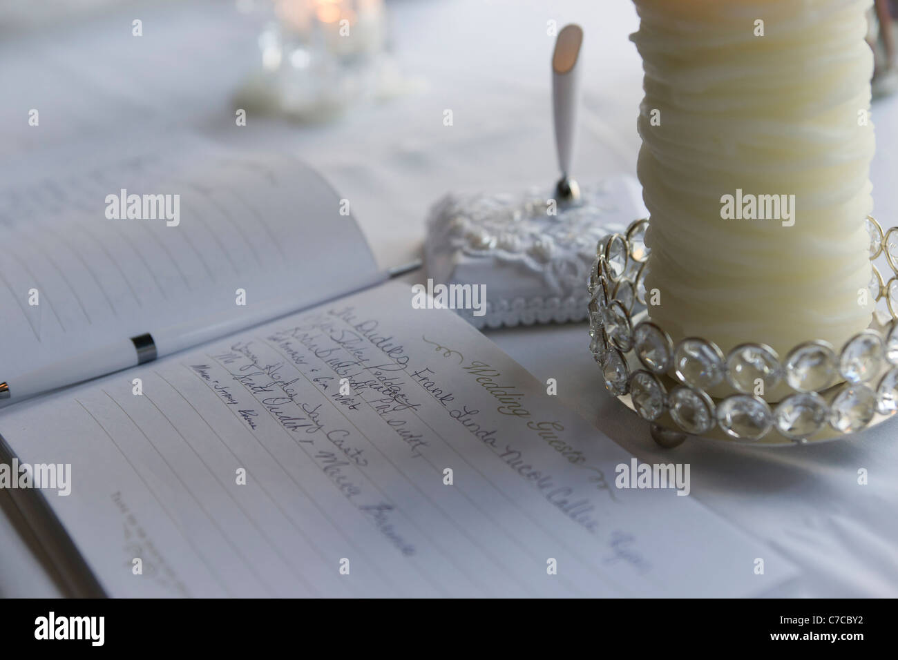 Libro per gli ospiti di matrimonio primo piano con penna, portapenne e grande candela sfocata sullo sfondo nessuno orizzontale negli Stati Uniti ad alta risoluzione Foto Stock