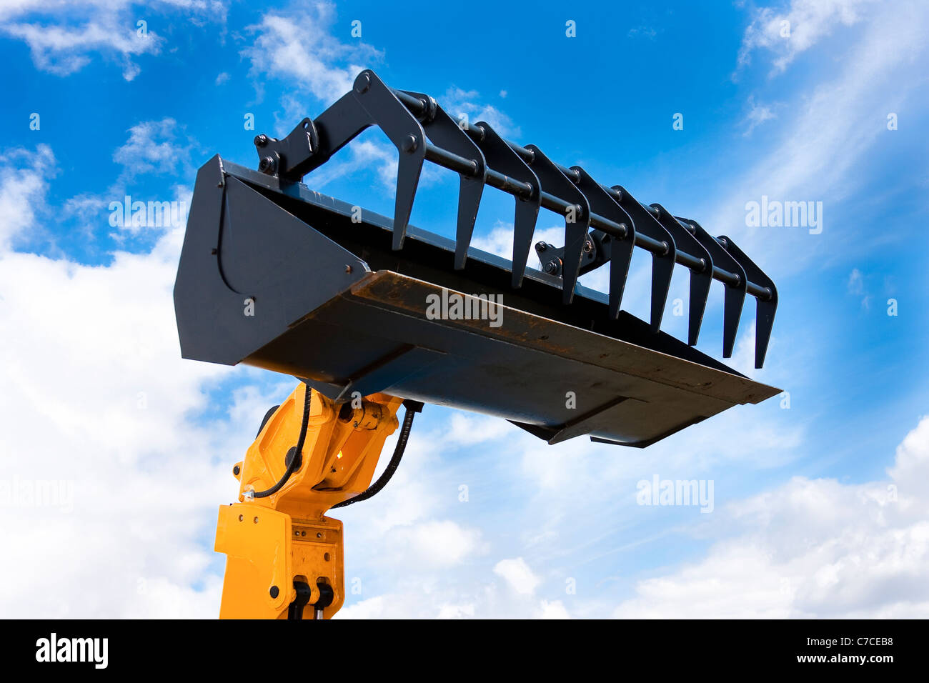 Giallo escavatore idraulico nero Grab benna isolata contro il cielo blu Foto Stock
