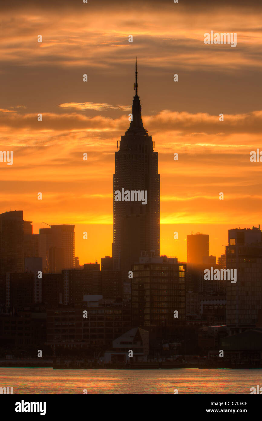Il sole splende da dietro l'Empire State Building poco dopo l'alba in New York City. Foto Stock