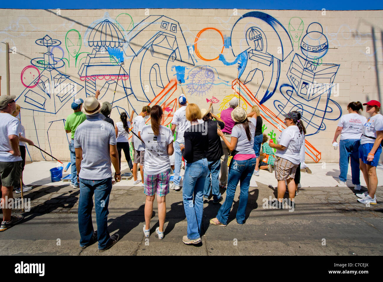 Artisti volontari dipingere una parete murale come parte di una comunità abbellimento progetto in Santa Ana CA. Foto Stock