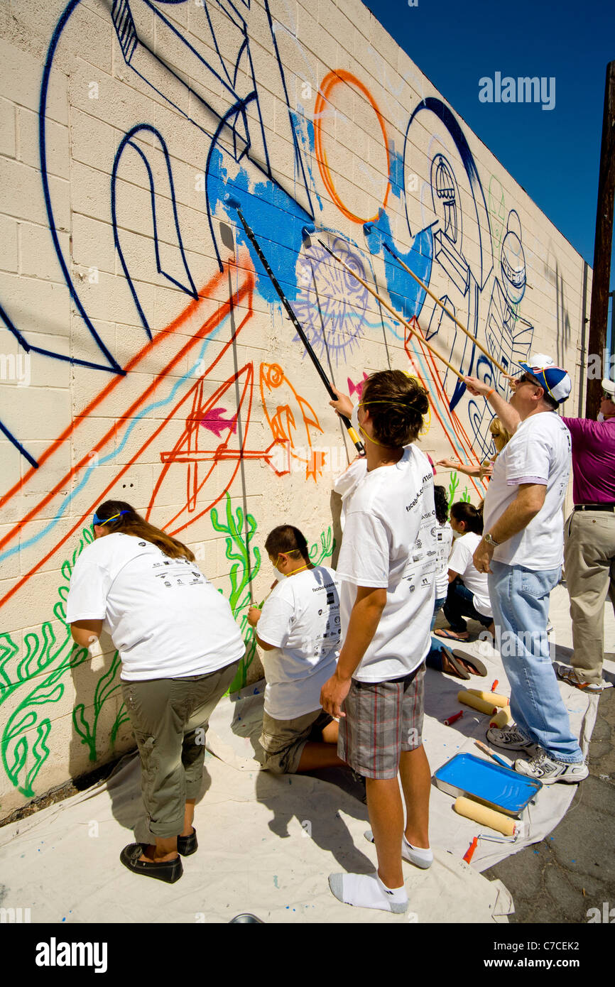 Artisti volontari dipingere una parete murale come parte di una comunità abbellimento progetto in Santa Ana CA. Foto Stock