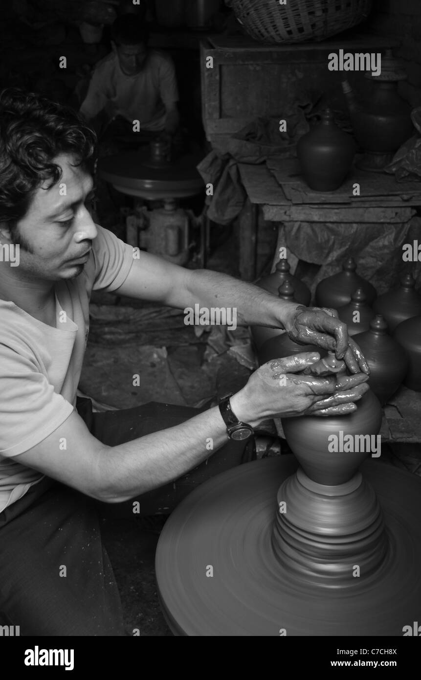 Un vasaio getta pentole sulla ruota, utilizzando locali di argilla grigia che gli incendi rosso terracotta, Bhaktapur, Nepal Foto Stock