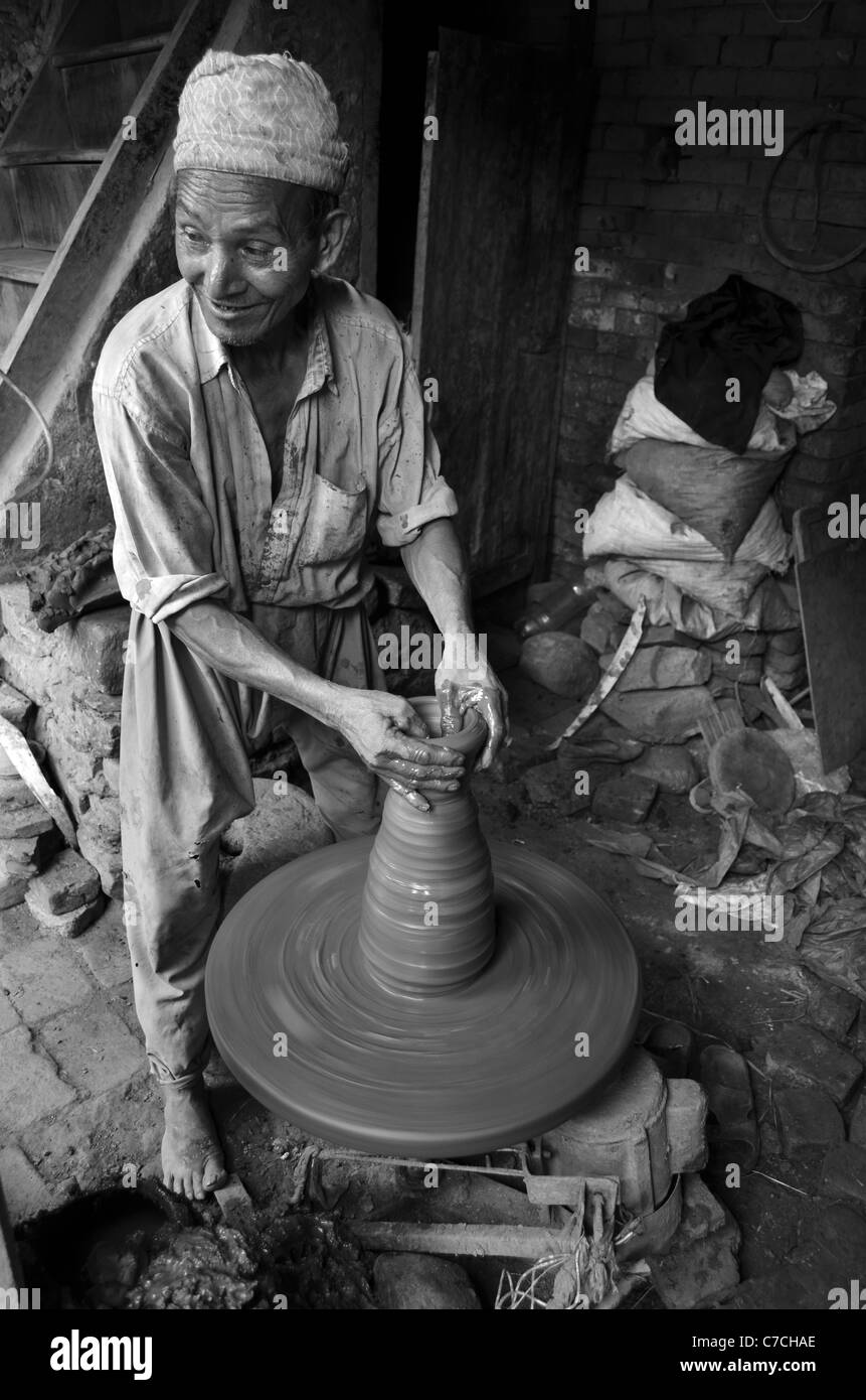 Un vasaio getta pentole sulla ruota, utilizzando locali di argilla grigia che gli incendi rosso terracotta, Bhaktapur, Nepal Foto Stock