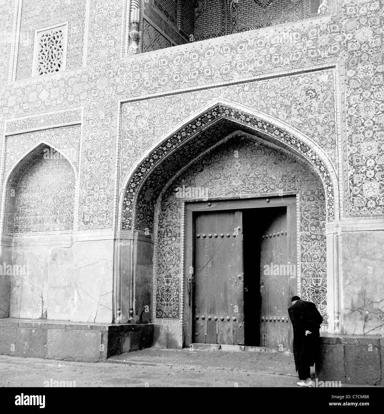 Storico degli anni cinquanta. Un vecchio uomo con testa inchinata all'ingresso del Masjid Shah, il Royal o la Moschea Blu, Isfahan, Iran. Foto Stock