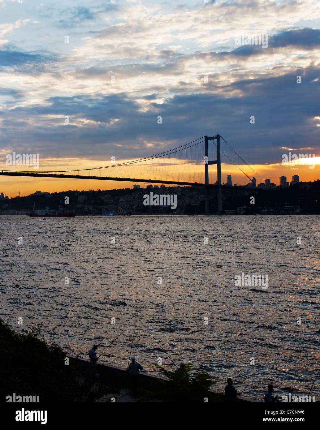 Fisherman pesca sul Bosphorus Istanbul per la loro cena, tramonto, nuvole oceano navi, bridge, ritratto di infrastruttura Foto Stock