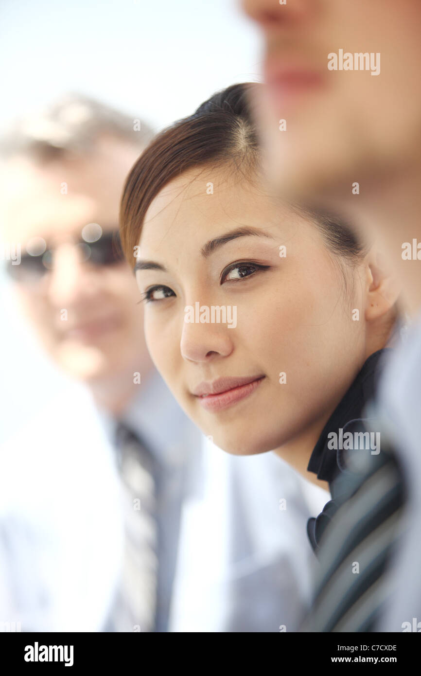 Giovane donna tra due colleghi, tutti vestiti bene in stile business, guardando la fotocamera e sorridente Foto Stock
