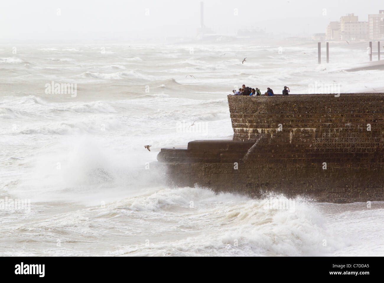 Guardando la tempesta, persone in piedi su un groyne guardando al mare, Brighton East Sussex, Regno Unito, autunno Foto Stock