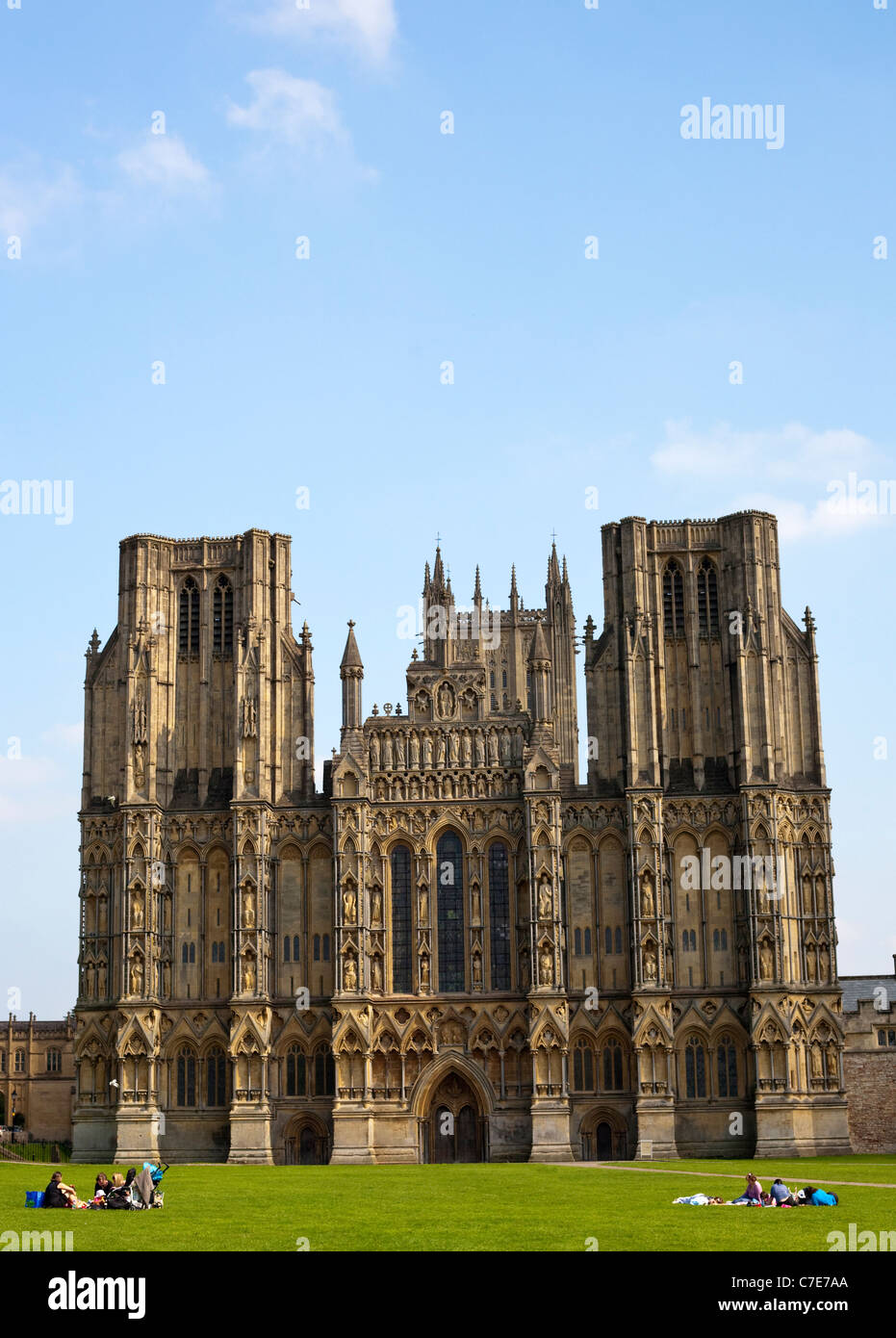 Cattedrale di Wells con un cielo blu in formato verticale con la gente sul prato Foto Stock