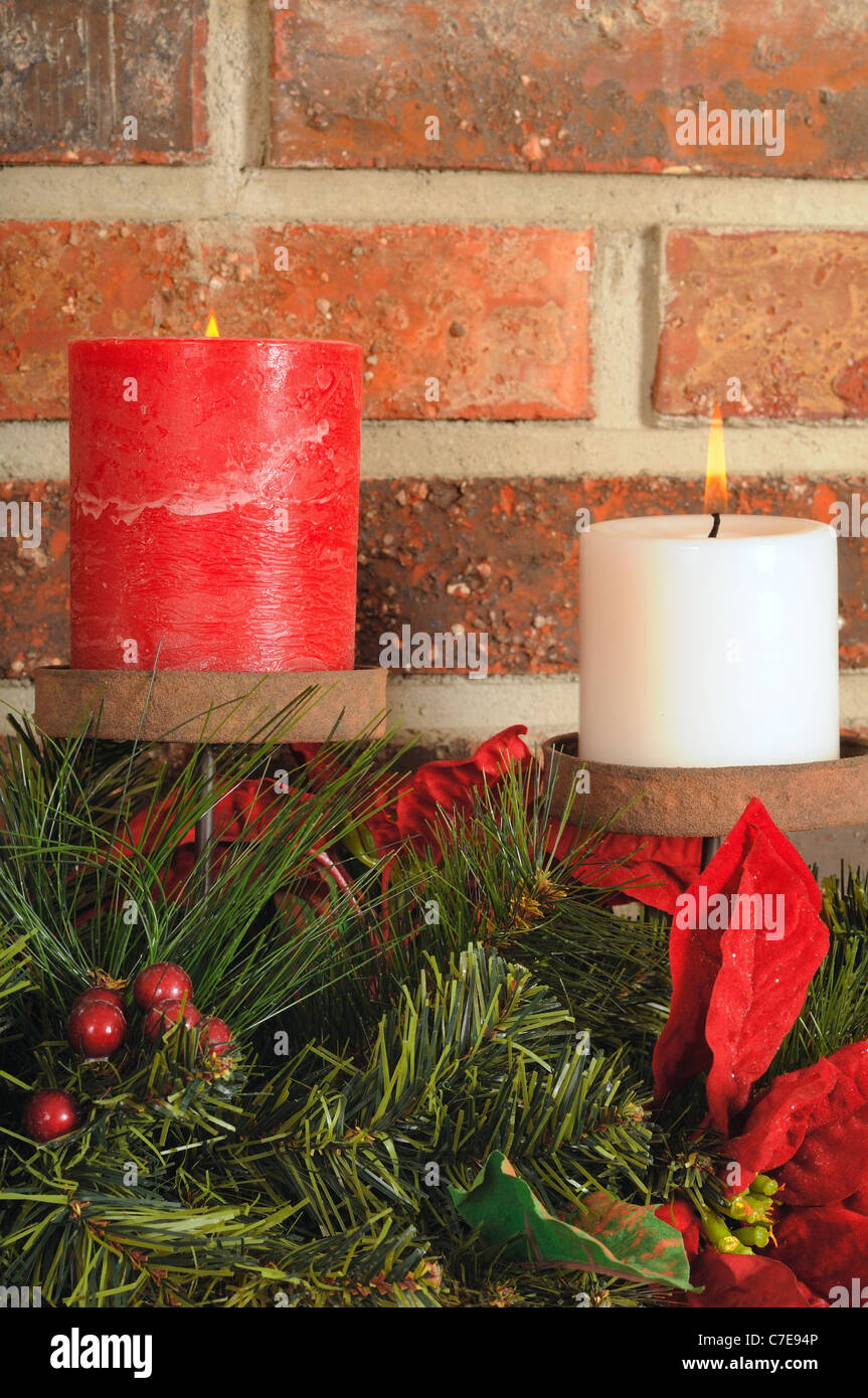 Due festa di Natale candele con verde su un mantello con Sfondo mattone Foto Stock