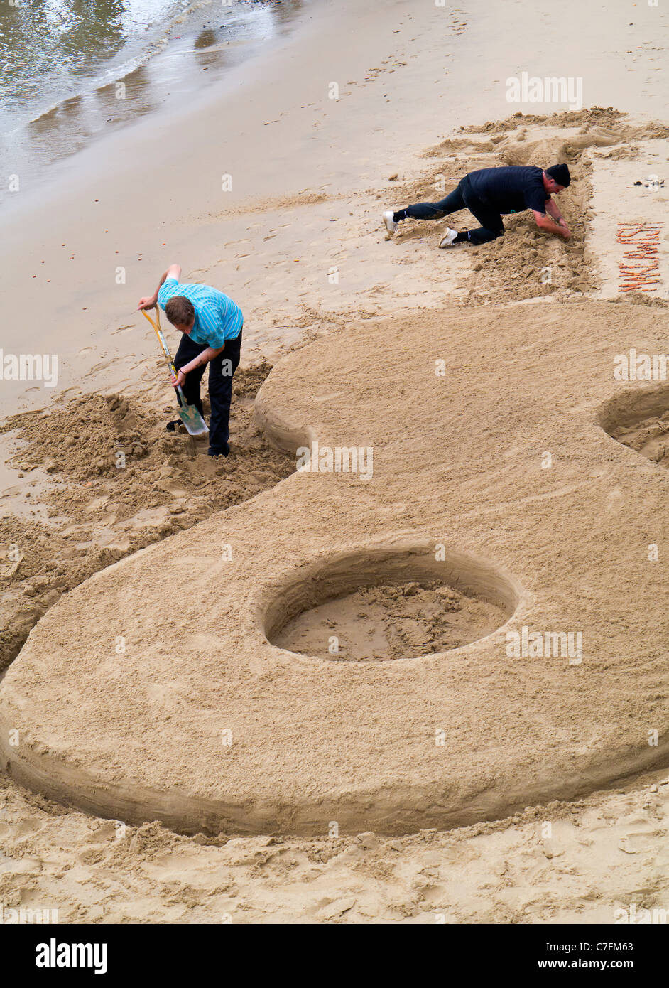 La costruzione di una chitarra gigante castello di sabbia con la bassa marea - Thames Festival Foto Stock