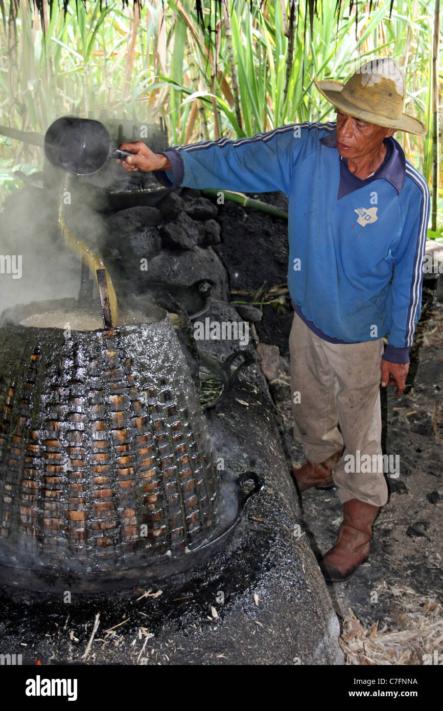 Uomo di Sumatra versa il succo di canna in pentola durante il villaggio di raffinazione dello zucchero di processo Foto Stock