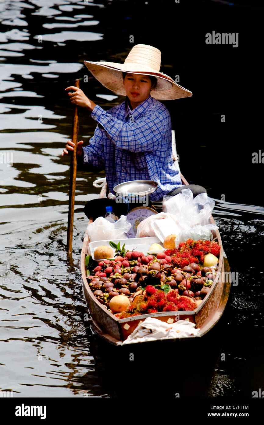 Una signora il canottaggio la sua barca riempito con frutta e fiori per il Dameon Saduk mercato galleggiante vicino a Bangkok, Thailandia. Foto Stock