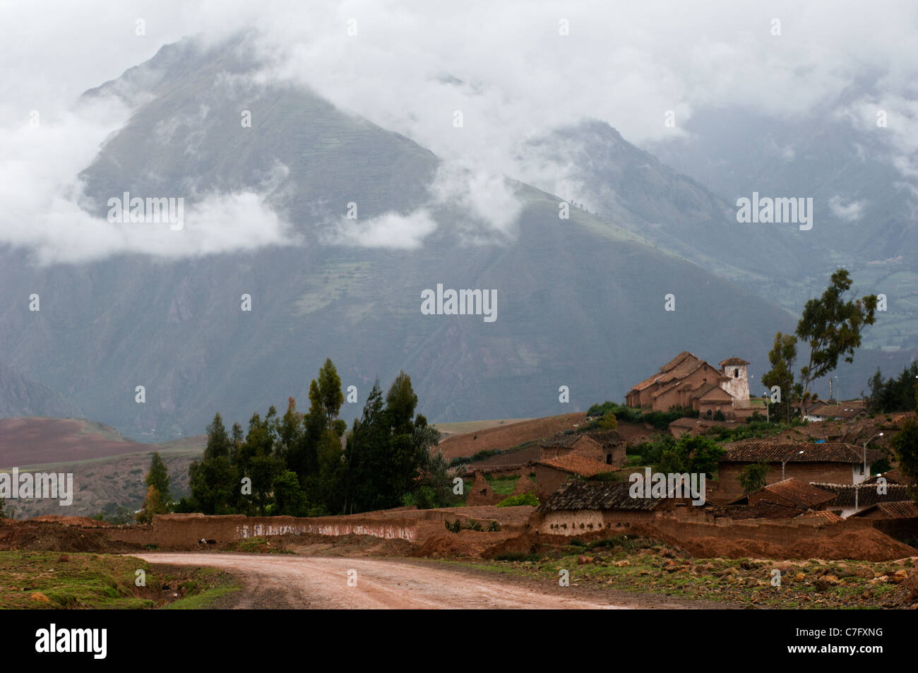 Piccolo villaggio nelle Ande. Piccole strutture contro le montagne i cui vertici sono coperti dalle nuvole. Foto Stock