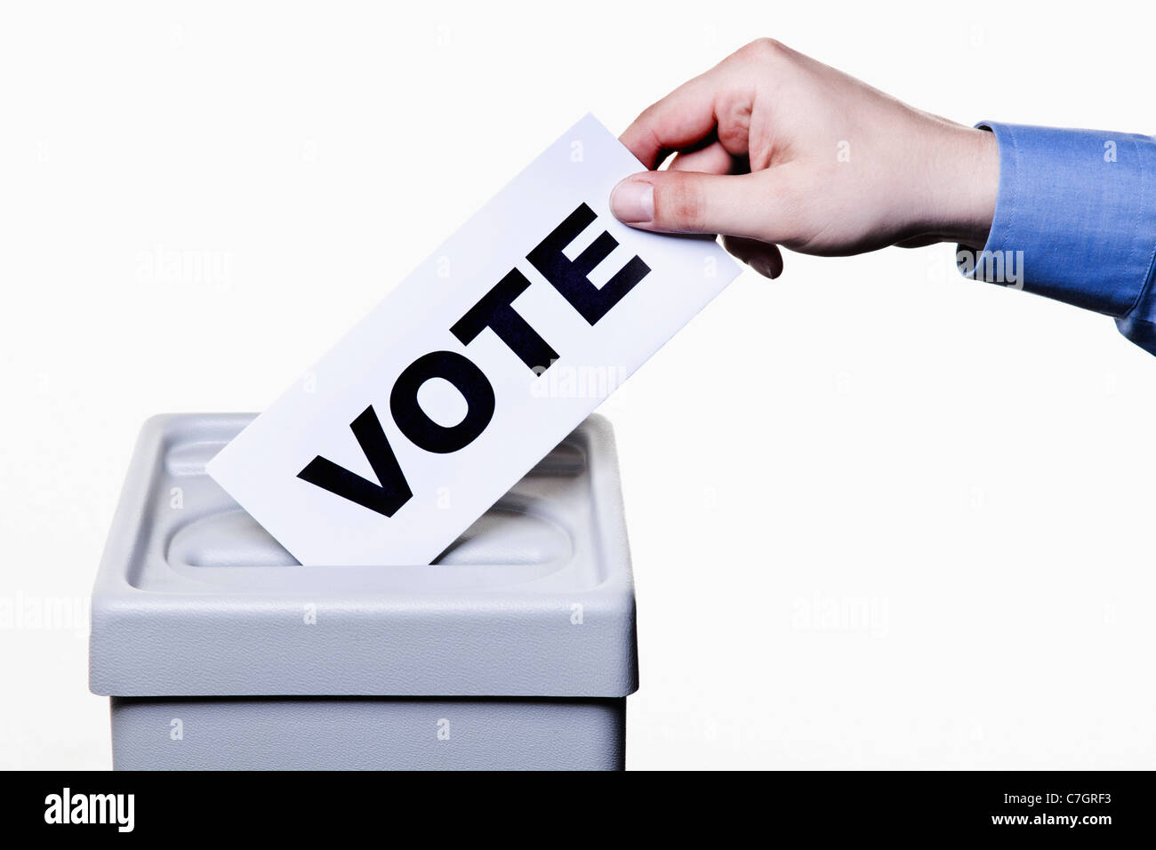 Un uomo mettendo un ballottaggio con la parola voto scritto su di esso in un urna, close-up le mani Foto Stock