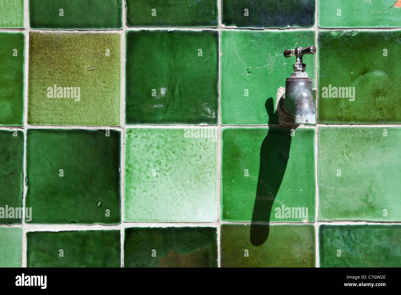 Un tap su un verde parete piastrellata Foto Stock