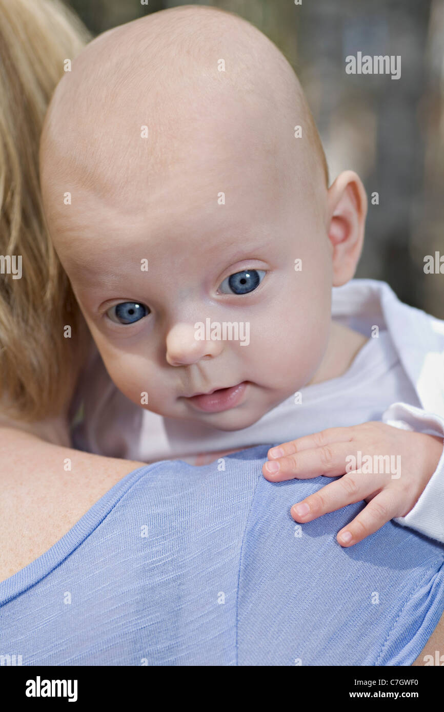Una madre tenendo un baby, oltre la spalla, concentrarsi sul bambino del volto Foto Stock
