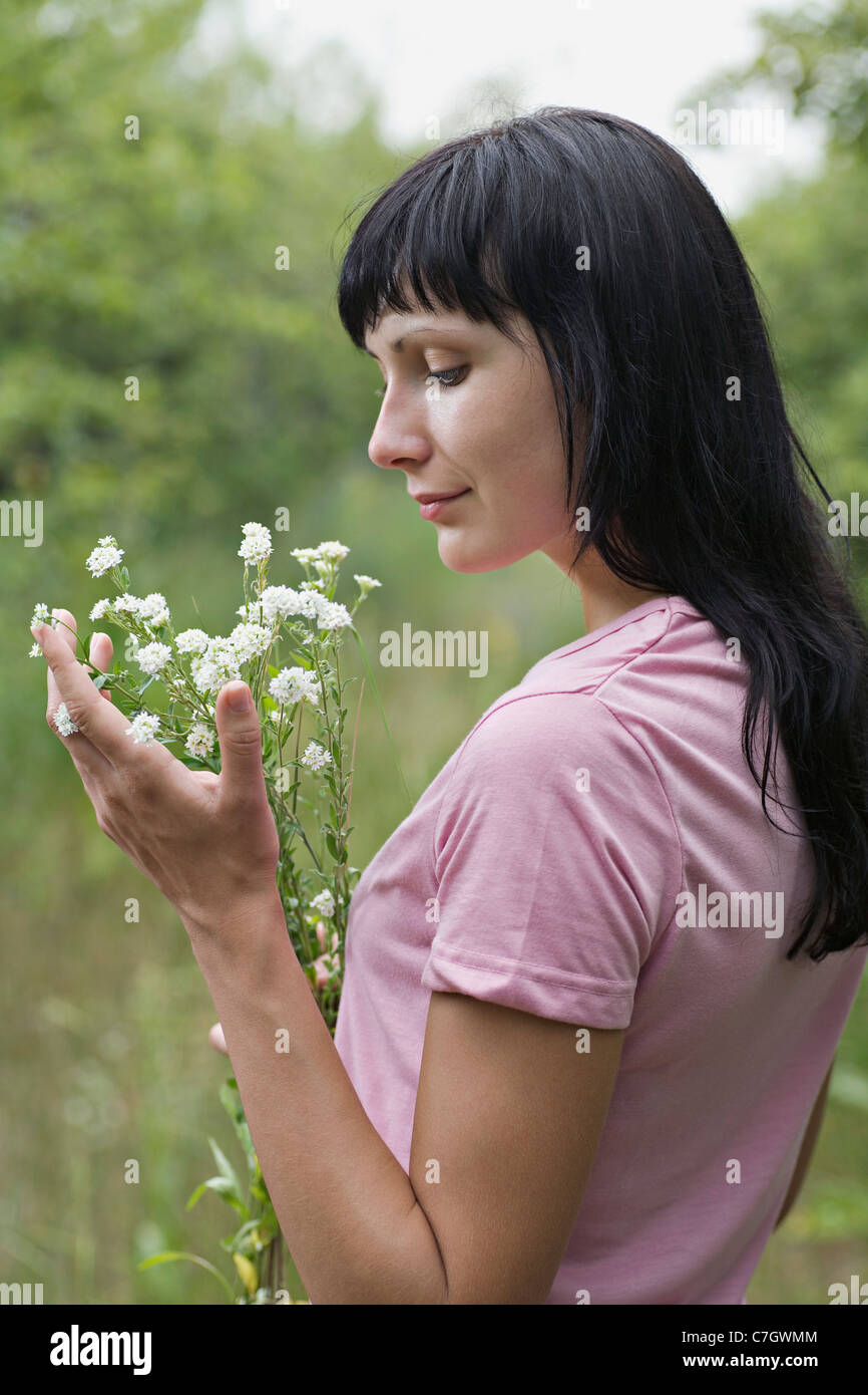 Una donna ammirando un mazzo di fiori selvatici che regge Foto Stock