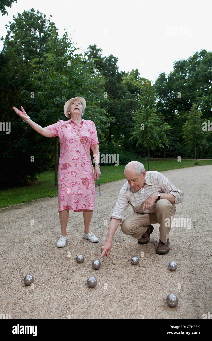 Senior l uomo e la donna hanno controversia giocando a bocce nel parco Foto Stock