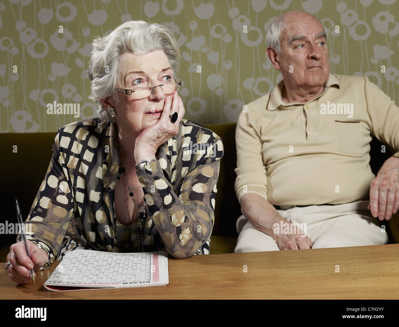 Senior donna lavora fuori magazzino puzzle con uomo senior in background Foto Stock