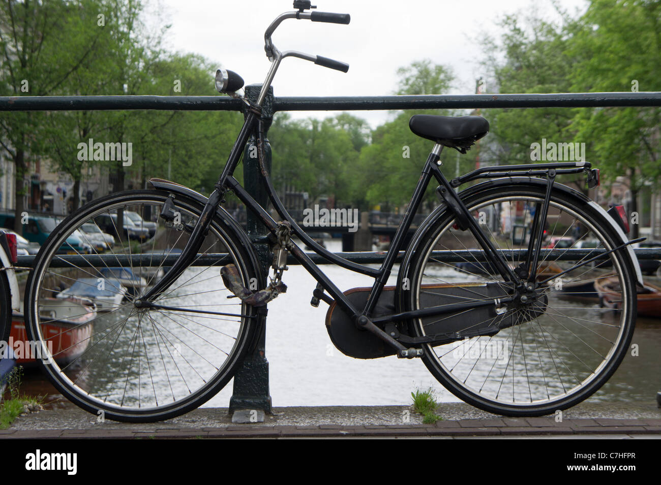 Vecchia bicicletta incatenati al ponte su un canale in Amsterdam, Olanda Foto Stock