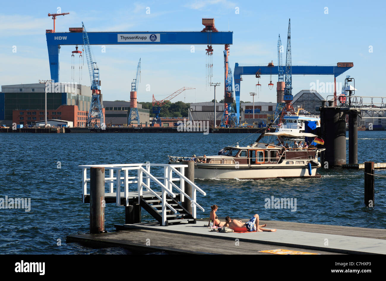 D-Kiel, Kiel Fjord, Mar Baltico, Schleswig-Holstein, porto di Kiel, vista dal Kiellinie al Howaldtswerke-Deutsche Werft, cantiere HDW, Thyssen Krupp, Gantry cranes, coppia giovane per prendere il sole Foto Stock