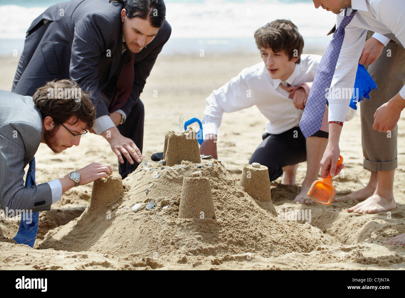 Imprenditori costruire castelli di sabbia Foto Stock