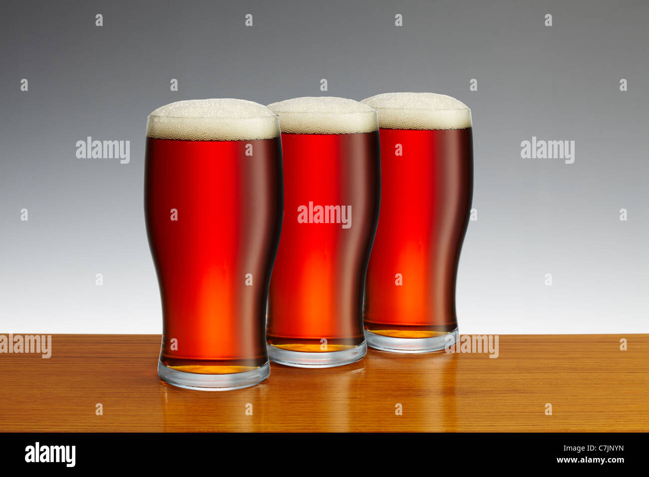 Tre pinte di birra sulla barra di legno top Foto Stock
