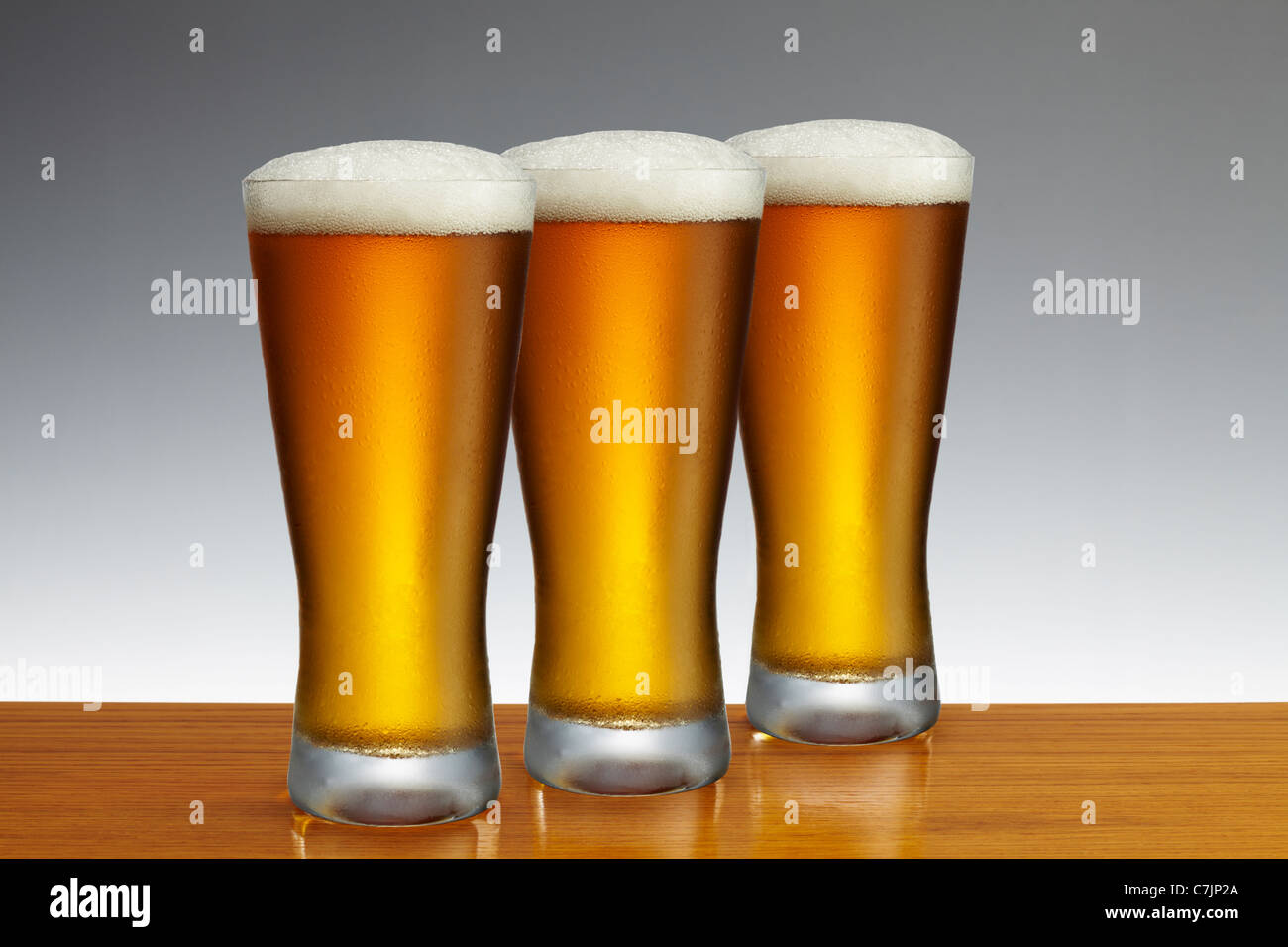 Tre pinte di birra lager su una barra di legno top Foto Stock