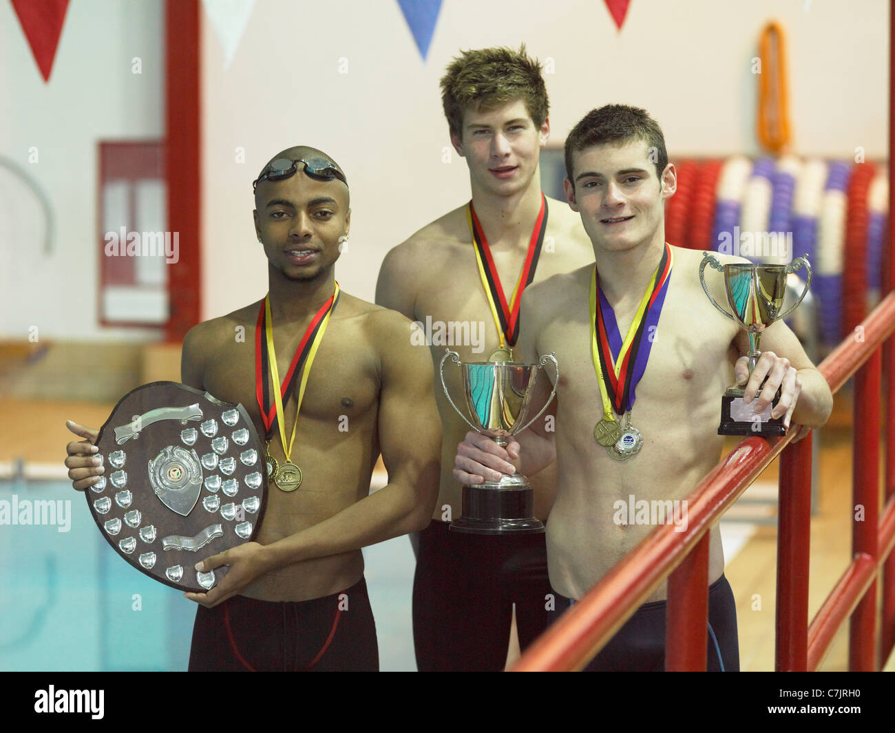 Nuotatori tenendo i trofei in piscina Foto Stock
