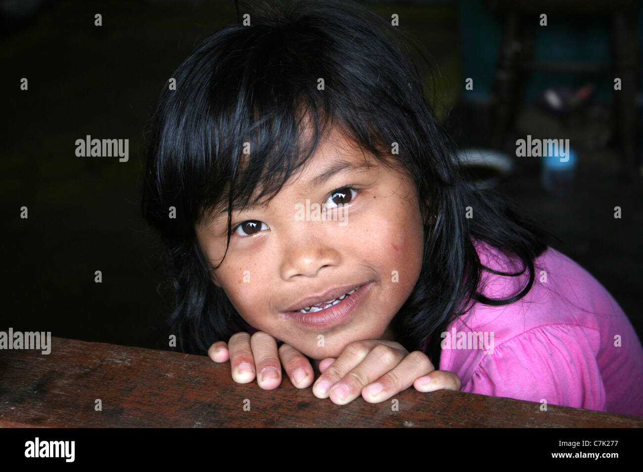 Giovani Karo Batak tribù picchi di ragazza al di sopra della finestra di casa sua, Sumatra Foto Stock