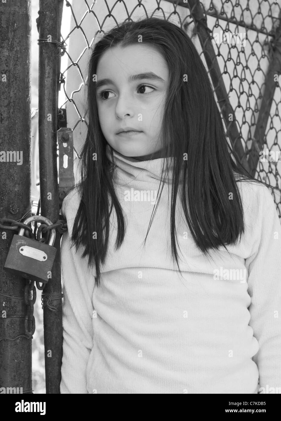 Triste e spaventata bambina davanti a un recinto di filo Foto Stock