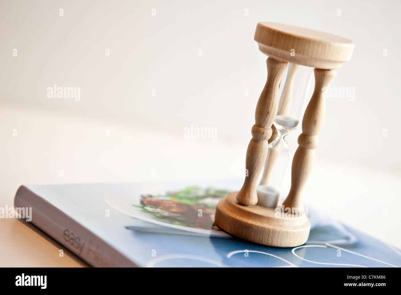 Un uovo di legno timer seduto su un sano libro di cucina Foto Stock
